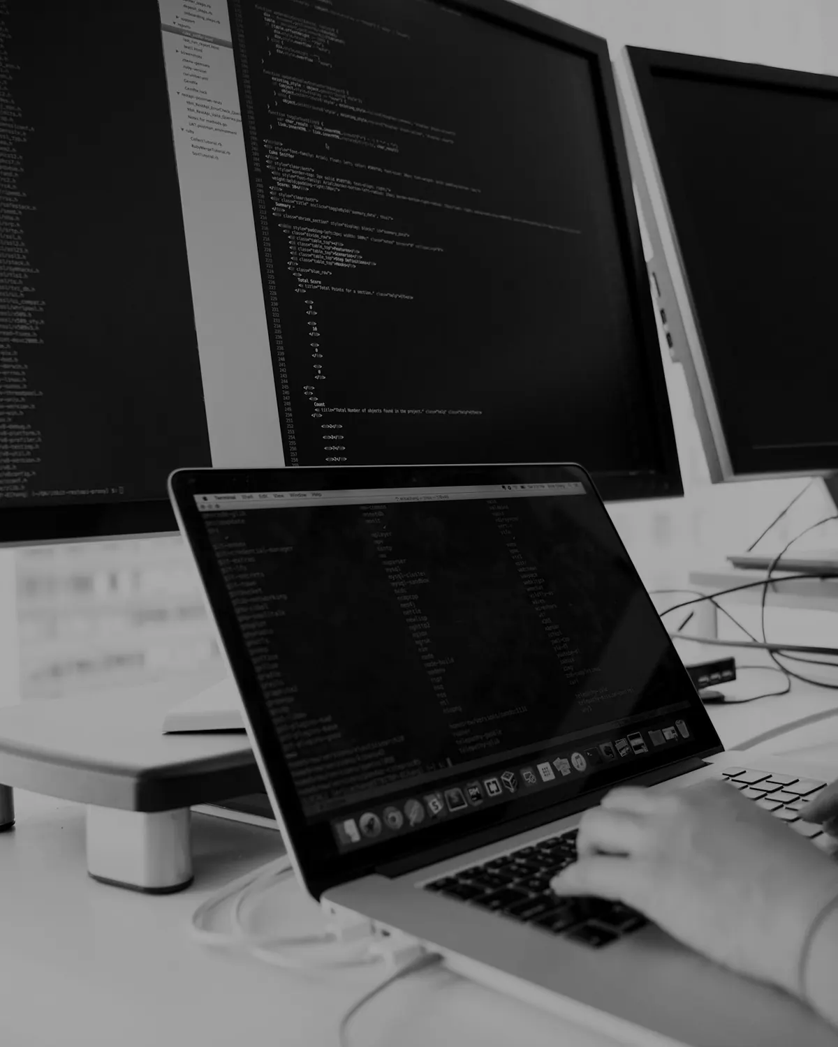 Hands on a keyboard in front of working screens