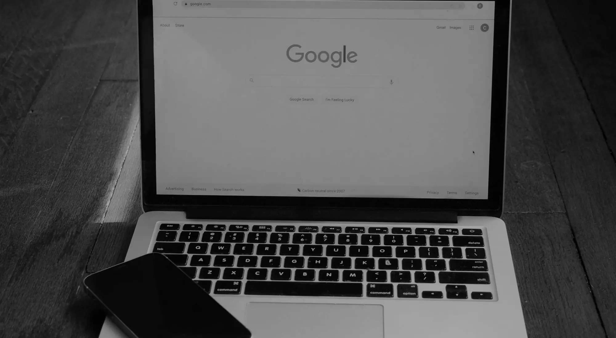 A laptop open on Google, a phone resting on the keyboard